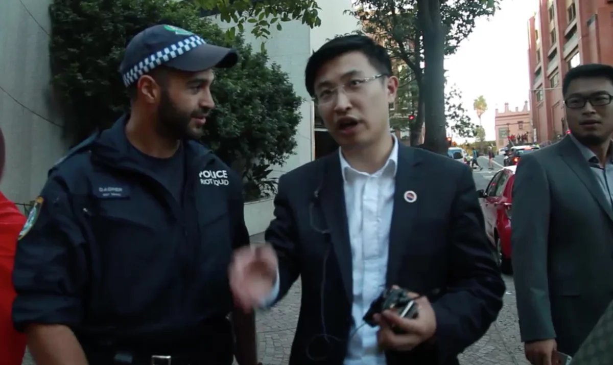 This screenshot shows an unidentified Chinese man (R) who, according to witnesses, was seen giving directions to the NSW police during Chinese leader Xi Jinping's visit to Sydney on Nov 18. (Screenshot from S.G. Hughes/YouTube) 