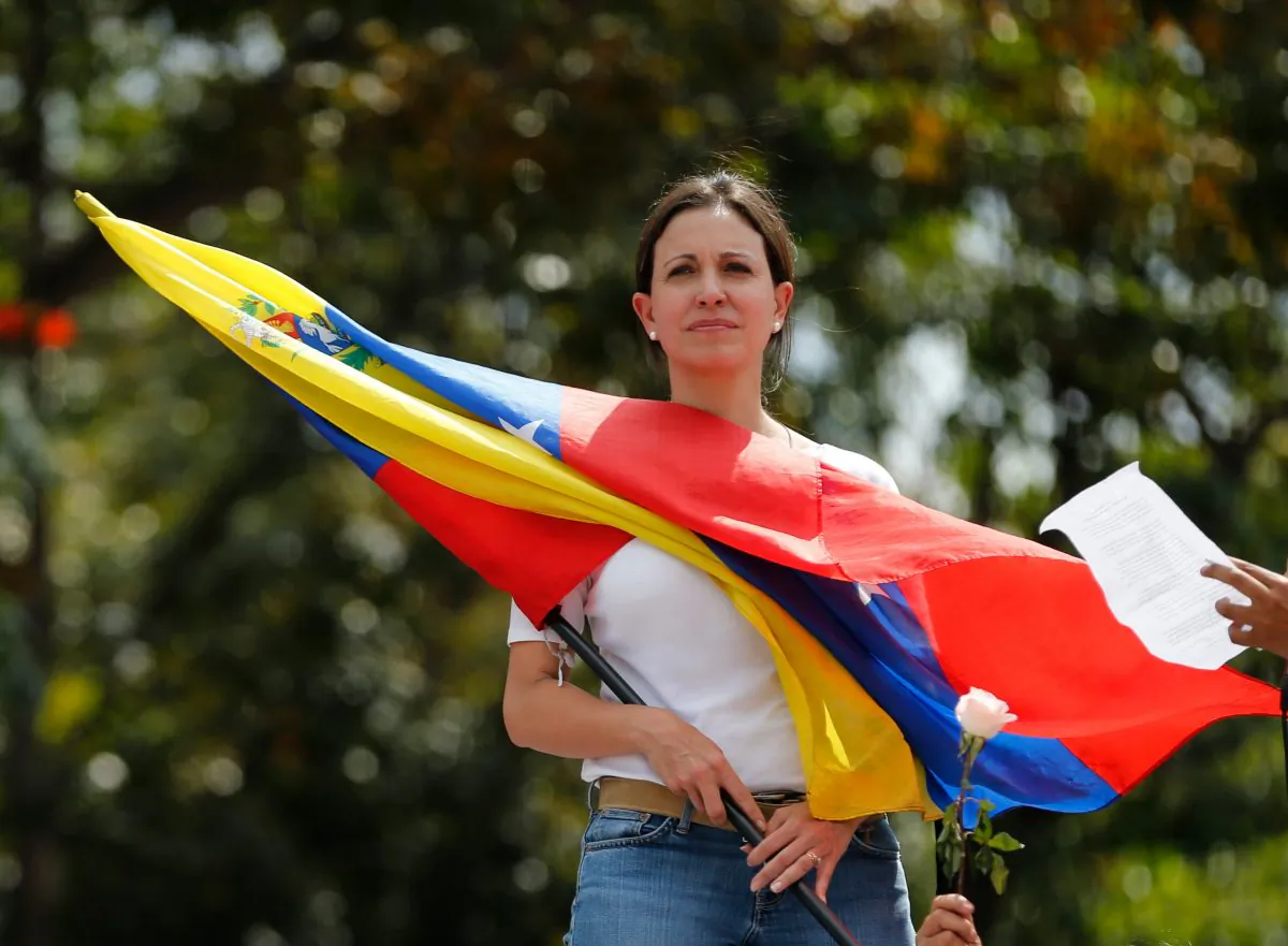 Opposition leader and Congresswoman Maria Corina Machado holds a Venezuelan flag during a women's protest outside the Bolivarian National Guard headquarters in Caracas, Venezuela, on Feb. 26, 2014. The outspoken leader of Venezuela’s opposition is being charged, Nov. 26, 2014, in what the government alleges was a US-backed plot to assassinate President Nicolas Maduro. (AP Photo/Fernando Llano)