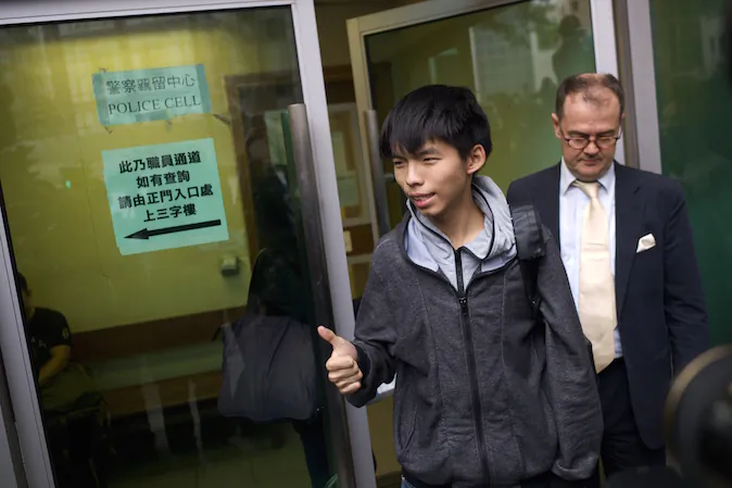 Student leader Joshua Wong gives a thumbs up as he exits a courthouse with his lawyer Michael Vidler after Wong was released on bail in Hong Kong on Nov. 27, 2014. (Aaron Tam/AFP/Getty Images)
