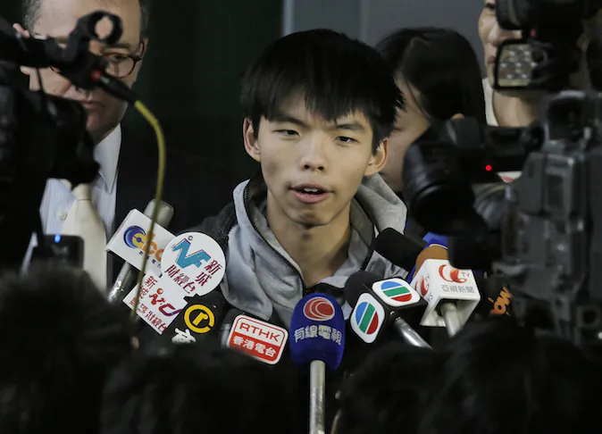 Prominent Hong Kong student protest leader Joshua Wong talks to reporters outside a court in Hong Kong Thursday, Nov. 27, 2014. Wong and other democracy protesters were arrested during a police operation to remove barricades from a protest camp in the unruly Mong Kok district. Wong was given bail and his case adjourned until January 14. (AP Photo/Vincent Yu)