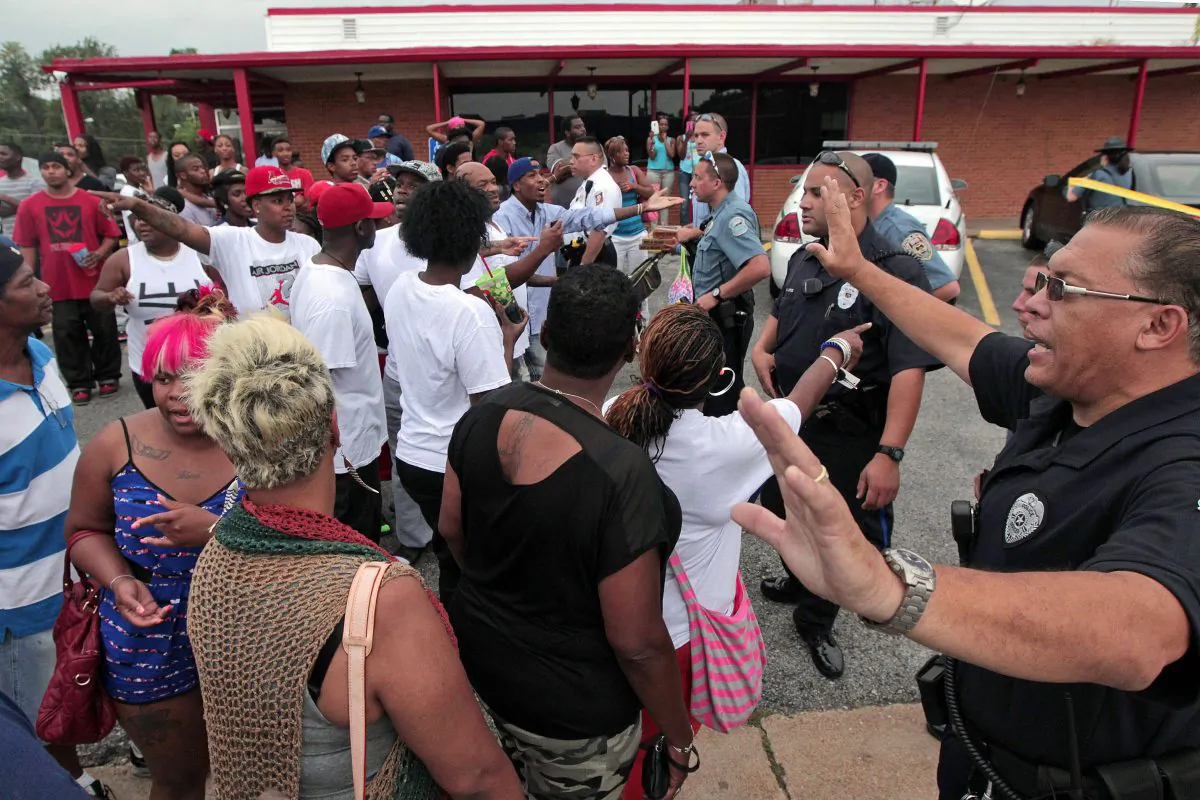 Ferguson police officers try to calm down a crowd on Aug. 9, 2014, near the scene where 18-year-old Michael Brown was fatally shot by a police officer in Ferguson, Mo. Departments around the country have in recent years stepped up their training in "de-escalation" — the art of defusing a tense situation with a word or a gesture instead of being confrontational or reaching for a weapon. (AP Photo/St. Louis Post-Dispatch, Huy Mach)