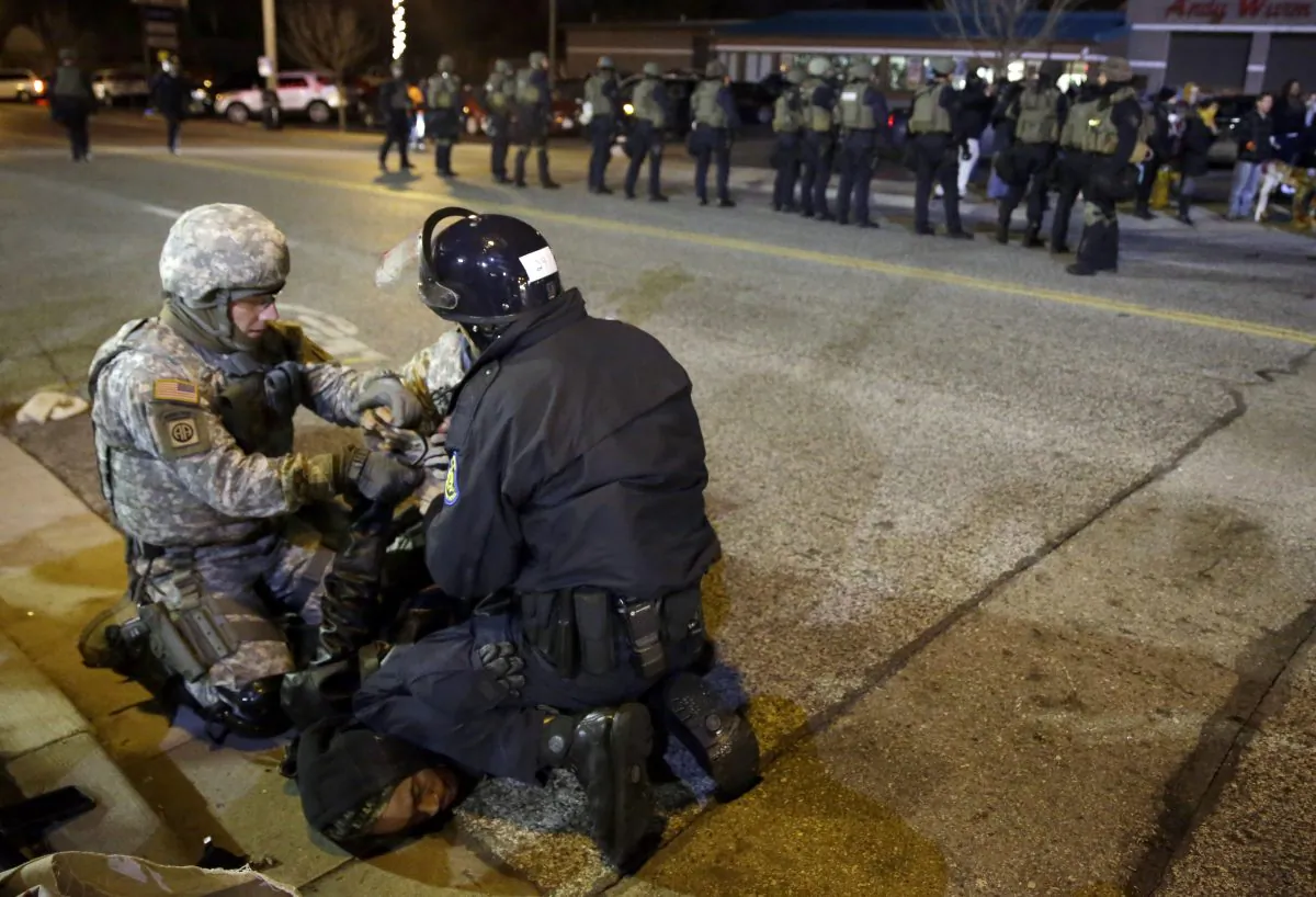 A protester is taken into custody Friday, Nov. 28, 2014, in Ferguson, Mo. Several protesters have been taken into custody during a demonstration outside the police department. Tensions escalated late Friday during an initially calm demonstration after police said protesters were illegally blocking West Florissant Avenue. (AP Photo/Jeff Roberson)