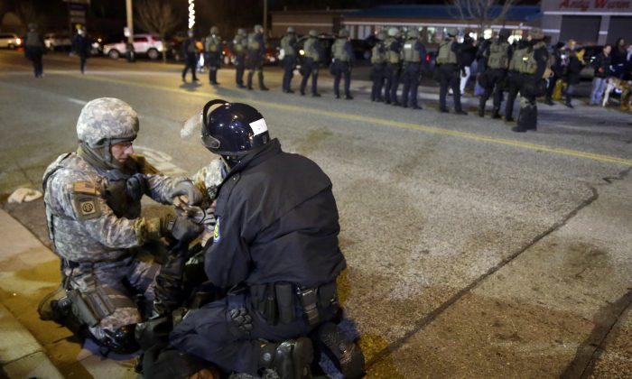 A protester is taken into custody Friday, Nov. 28, 2014, in Ferguson, Mo. Several protesters have been taken into custody during a demonstration outside the police department. Tensions escalated late Friday during an initially calm demonstration after police said protesters were illegally blocking West Florissant Avenue. (AP Photo/Jeff Roberson)