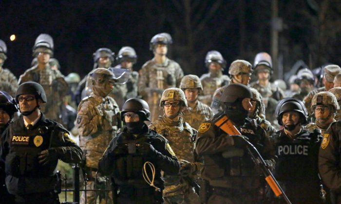 Police and Missouri National Guardsmen stand guard as protesters gather in front of Ferguson Police Department on Friday, Nov. 28, 2014, in Ferguson, Mo. Several protesters have been taken into custody during a demonstration outside the police department. Tensions escalated late Friday during an initially calm demonstration after police said protesters were illegally blocking West Florissant Avenue. (AP Photo/Jeff Roberson)