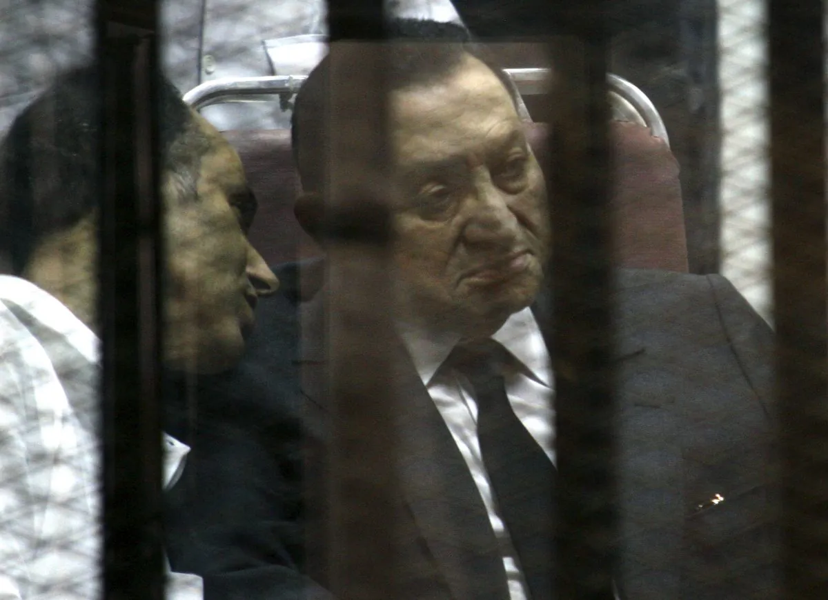 Ousted Egyptian President Hosni Mubarak sits in the defendants cage behind protective glass during a court hearing as he listens to his son Gamal, left, in Cairo, Egypt, May 21, 2014. Egypt court on Saturday, Nov. 29, dismissed criminal charges against Mubarak in the killing of more than 900 protesters during the 2011 uprising against his rule. (AP Photo/Tarek el-Gabbas)
