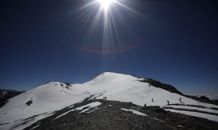 In this June 12, 2011 file photo, people walk along the Cordillera Real of the Andes mountains on the outskirts of La Paz, Bolivia. According to the Environmental Defense League, a Bolivian NGO, Bolivia's glaciers along the Cordillera Real, Chacaltaya, Tuni Condorini and Illimani are shrinking in size by more than one meter every year and estimate that the majority of the snow in this area could disappear by 2030. A scientific assessment by the U.N.’s expert panel on climate change warned that rising global temperatures could have an irreversible impact on people and ecosystems as glaciers melt, sea levels rise, heat waves intensify and oceans become warmer and more acidic. (AP Photo/Juan Karita)