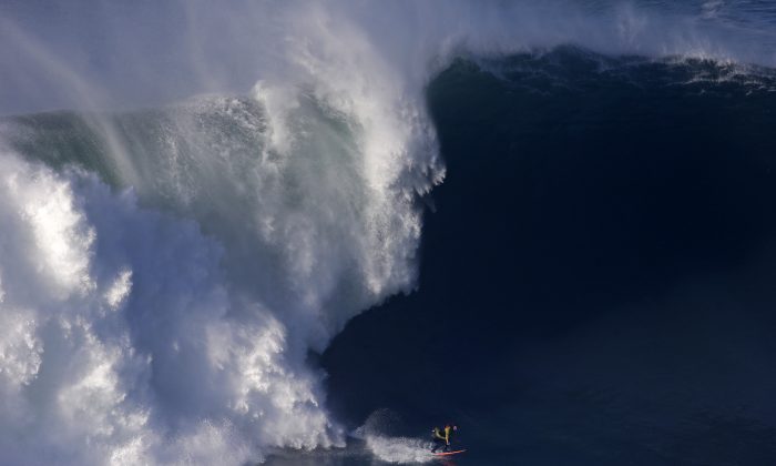 A surfer rides a big wave during a tow-in surfing session at the Praia do Norte or North beach, in Nazare, Portugal, on Nov. 29, 2014. The beach has become a famous spot for big wave surfers around the world after Hawaiian surfer Garrett McNamara set a world record for the largest wave surfed in 2011. (AP Photo/Francisco Seco)