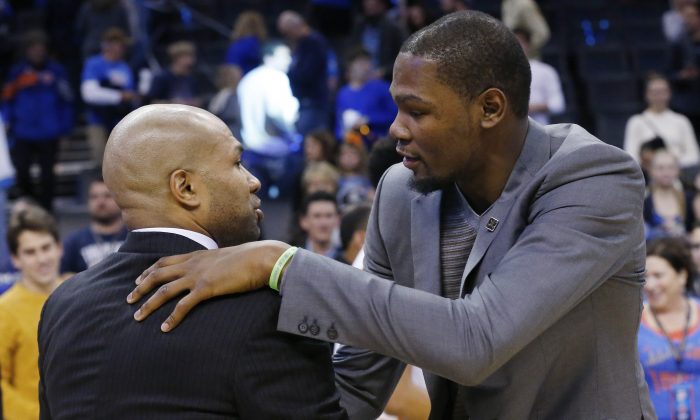 Injured Oklahoma City Thunder's Kevin Durant, right, embraces New York Knicks head coach Derek Fisher, left, following their NBA basketball game in Oklahoma City, Friday, Nov. 28, 2014. Oklahoma City won 105-78. (AP Photo/Sue Ogrocki)