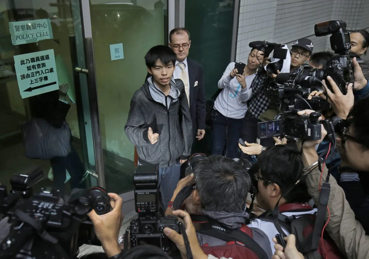 Prominent Hong Kong student protest leader Joshua Wong, center, walks out from a court with his lawyer in Hong Kong, Thursday, Nov. 27, 2014. (AP Photo/Vincent Yu)