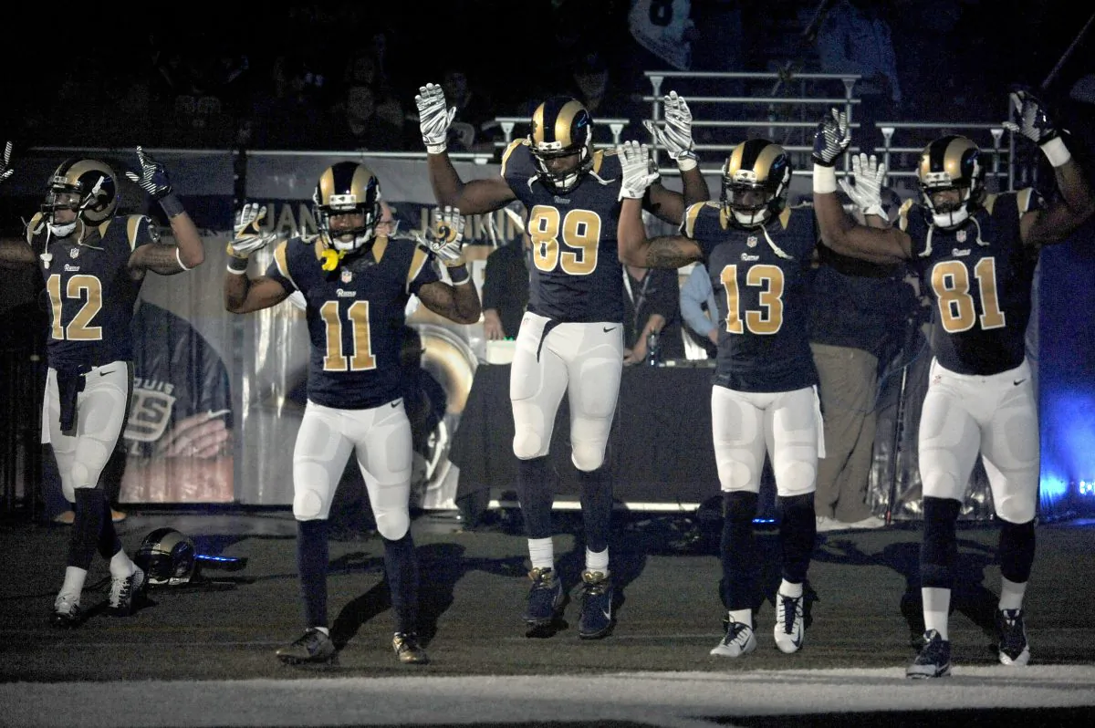 Members of the St. Louis Rams raise their arms in awareness of the events in Ferguson, Mo., as they walk onto the field during introductions before an NFL football game against the Oakland Raiders, Sunday, Nov. 30, 2014, in St. Louis. From left are Stedman Bailey (12), Tavon Austin (11), Jared Cook, (89) Chris Givens (13) and Kenny Britt (81). The players said after the game, they raised their arms in a "hands up" gesture to acknowledge the events in Ferguson. (AP Photo/L.G. Patterson)