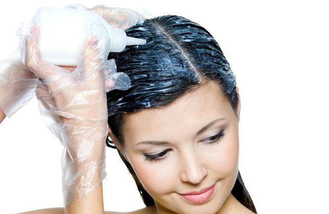 Young woman applying commercial hair dye to her hair. (Shutterstock)