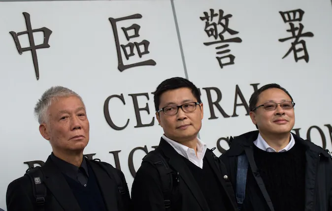 Benny Tai (R), an original founder of the pro-democracy Occupy movement, Chu Yiu-ming (L) and Chan Kin-man surrender to police in Hong Kong on December 3, 2014. (Johannes Eisele/AFP/Getty Images)