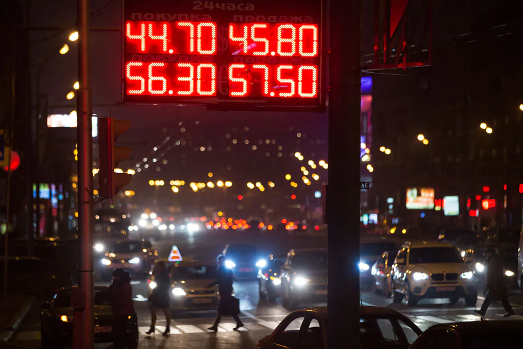 People cross a street next to a display with exchange rates in downtown Moscow on Monday, Nov. 10, 2014, showing the rate against the dollar, (top) and the euro (bottom). Russia's Central Bank on Monday scrapped its daily controls on the value of the ruble, allowing the battered currency to float freely in financial markets earlier than planned. The bank, which had planned to let the ruble trade freely starting next year, made the move as the currency has come under sustained pressure in the face of Western sanctions over Ukraine and plummeting oil prices. The ruble has lost nearly half its value against the dollar this year. (AP Photo/Pavel Golovkin)