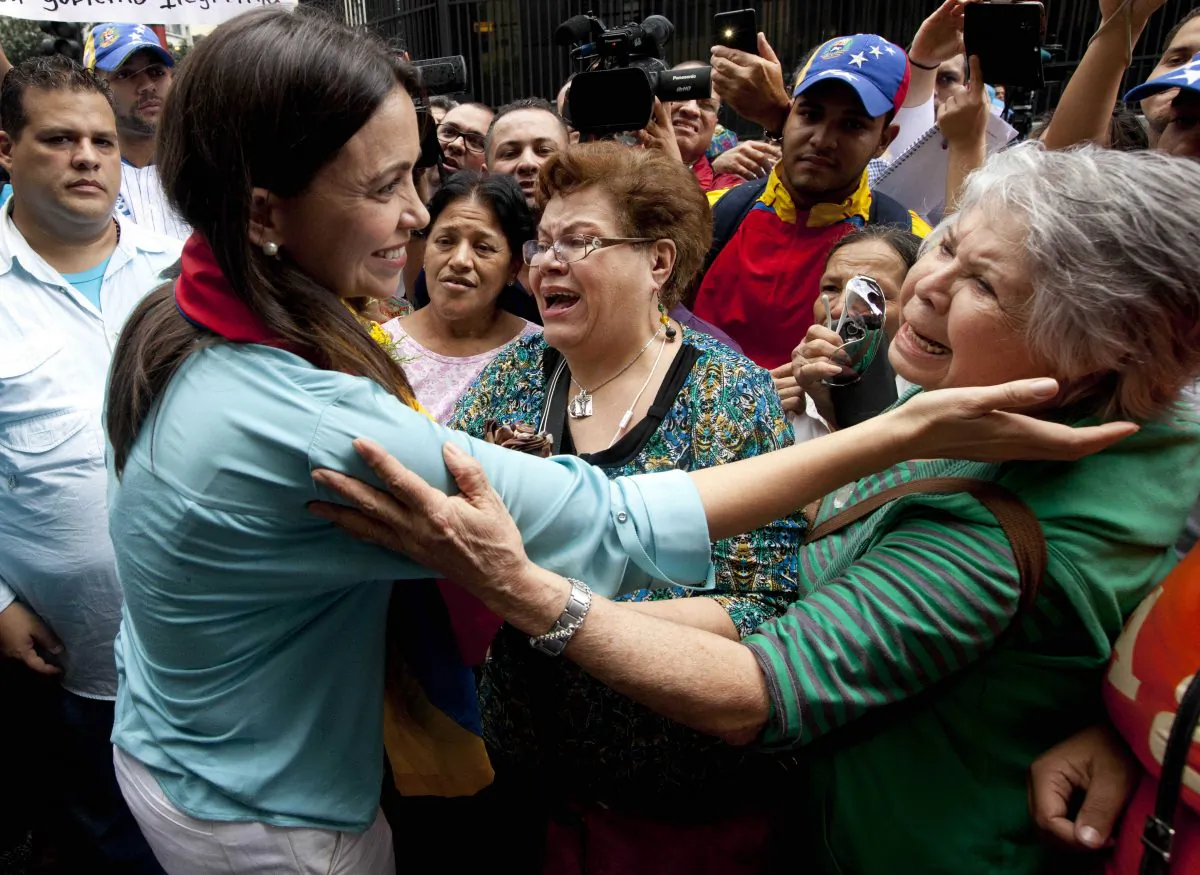 Former Congresswoman and opposition leader Maria Corina Machado (L) greets supporters as she exits the Attorney General Office in Caracas, Venezuela, Wednesday, Dec. 3, 2014. Machado appeared in court to testify after being charged with conspiring to assassinate Venezuela's President Nicolas Maduro. Machado, 47, was prohibited from leaving the country in June after she was removed from her National Assembly seat by the ruling party. (AP Photo/Ariana Cubillos)