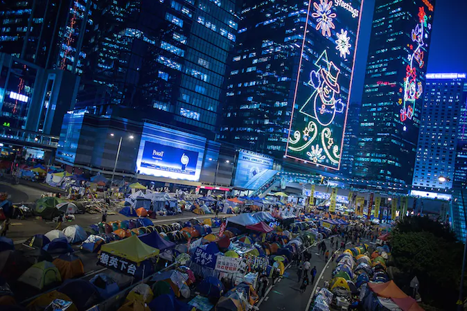 Pro-democracy protesters walk past tents at protest site in the Admiralty district on December 3, 2014 in Hong Kong. (Lam Yik Fei/Getty Images)