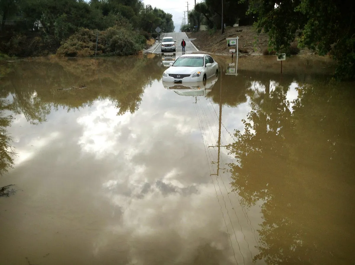 A car sits partially submerged in flood waters on Hemet Street in Hemet, Calif., Thursday morning, Dec. 4, 2014, after overnight rains doused the area. A second day of much-needed rain is falling across drought-stricken California. (AP Photo/The Press-Enterprise, Craig Shultz)