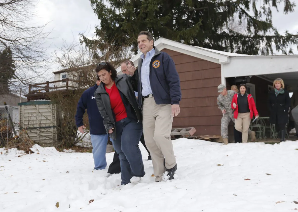New York Gov. Andrew Cuomo (R) helps resident Nancy Barletta through the snow at her house in West Seneca, N.Y., on Monday, Nov. 24, 2014. The billionaire appointed by Gov. Andrew Cuomo to oversee the Thruway Authority has resigned. (AP Photo/Mike Groll)