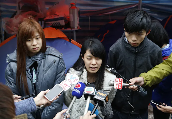 Three students, from right, Joshua Wong, Prince Wong and Isabella Lo speak to the media during their hunger strike at the occupied area outside government headquarters in Hong Kong on Tuesday, Dec. 2, 2014. (AP Photo/Kin Cheung)