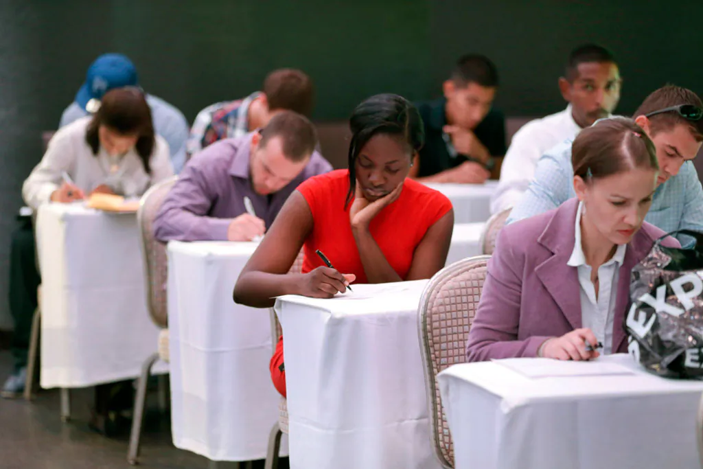 Job seekers fill out forms before being interviewed during a job fair at Fontainebleau Miami Beach in Miami Beach, Fla., on Oct. 6, 2014. The recovery of the U.S. job market has reached a new milestone on its road to full health: For the first time since the Great Recession ended 5½ years ago, America’s unemployed are now as likely to be hired as to stop looking for a job. (AP Photo/Wilfredo Lee)
