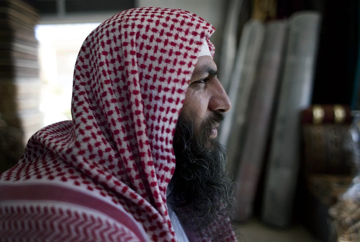 Salafi cleric Mohammed al-Shalabi, 48, widely known as Abu Sayyaf, talks during an interview with the Associated Press at a furniture store, owned by the head of Abu Sayyaf's clan, in the city of Ma'an, Jordan, on Oct. 29, 2014. Local authorities quickly stripped away public signs of support for the Islamic State group in this desert town. Black flags have been removed from rooftops. Graffiti proclaiming the extremists imminent victory have been whitewashed. But supporters of the Middle Easts most radical extremist group are only laying low. (AP Photo/Nasser Nasser)