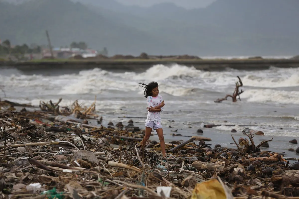 A girl walks along the shore as strong waves from Typhoon Hagupit hit Atimonan, Quezon province, eastern Philippines on Saturday, Dec. 6, 2014. Haunted by Typhoon Haiyan's massive devastation last year, more than 600,000 people fled Philippine villages and the military went on full alert Saturday to brace for a powerful storm only hours away from the country's eastern coast. (AP Photo/Aaron Favila)