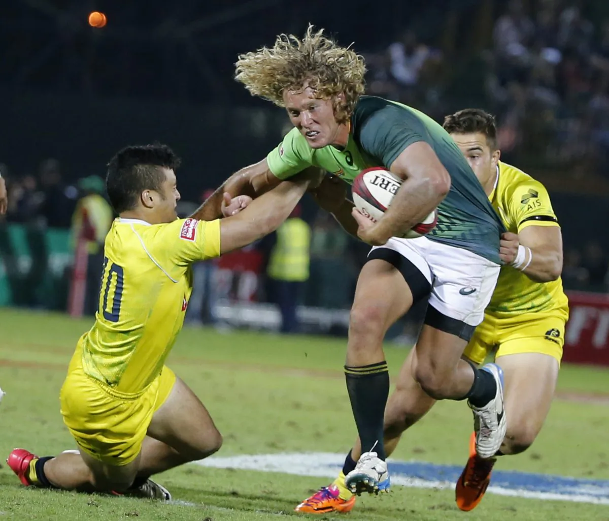 Werner Kok (C) of South Africa is tackled by Allan Faalavaau (L) and Greg Jeloudev of Australia during the final of the Emirates Airlines Dubai Sevens on December 6, 2014. The 2014/15 World Seven Series began in Australia's Gold Coast last month and will now see the 16 teams move on to Port Elizabeth, South Africa for the next leg of the series to be played this coming weekend Dec 13-14. (KARIM SAHIB/AFP/Getty Images)