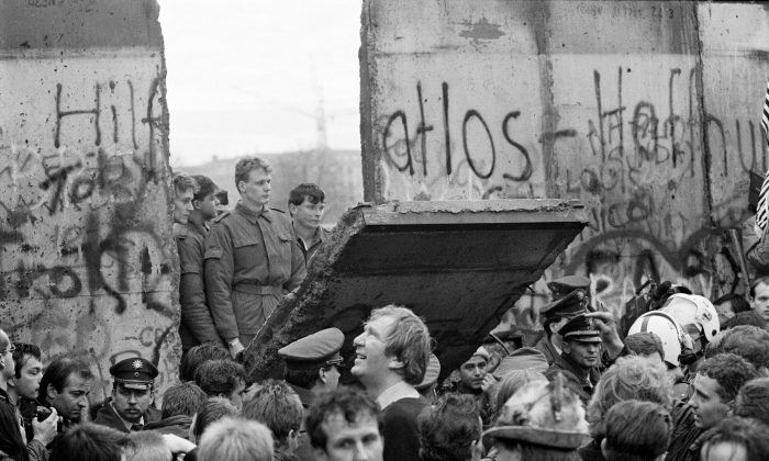West Berliners crowd in front of the Berlin Wall early Nov. 11, 1989, as they watch East German border guards demolishing a section of the wall in order to open a new crossing point between East and West Berlin, near the Potsdamer Square. (Gerard Malie/AFP/Getty Images)