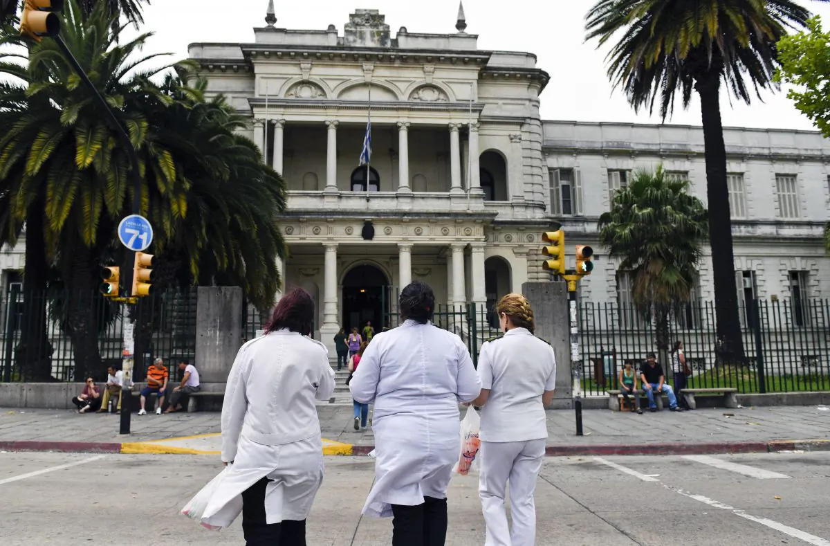 Three doctors enter the military hospital in Montevideo, Uruguay, Sunday, Dec. 7, 2014. (AP Photo/Matilde Campodonico)