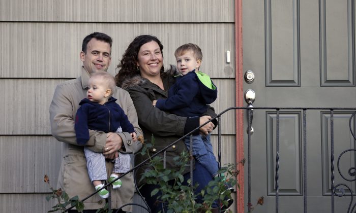 Jennifer Ewing, and her husband Florian Thiel hold their children Max (R), 3, and Felix, 8-months, as they pose for a photo on the steps of their new home in Seattles Ballard neighborhood, on Oct. 15, 2014. The couple recently closed on the three-bedroom house , which cost slightly less than $500,000. They moved to Seattle from New York, another city that matches the pattern of high-income jobs and even more expensive housing. (AP Photo/Elaine Thompson)