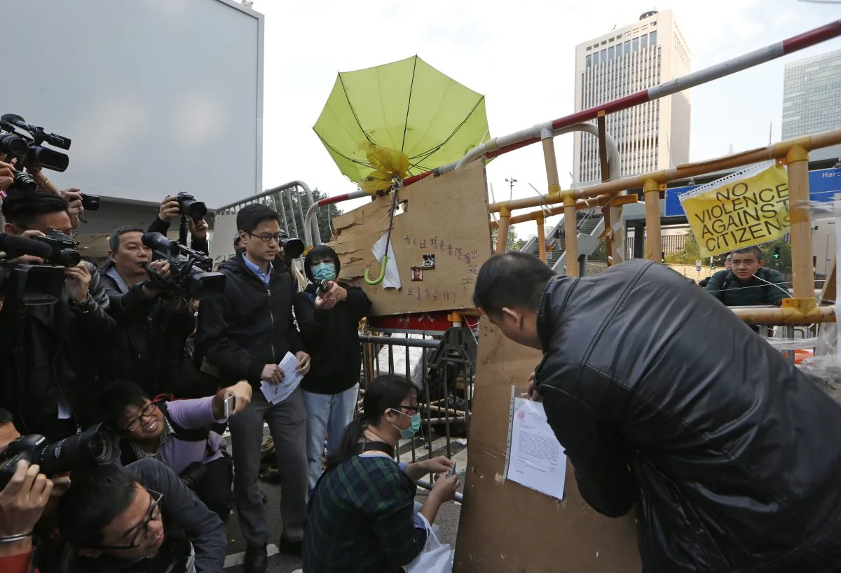 A bailiff member puts up an injunction document issued by a court, on a barricade set up by pro-democracy protesters at the occupied area outside government headquarters in Hong Kong Tuesday, Dec. 9, 2014. (AP Photo/Kin Cheung)
