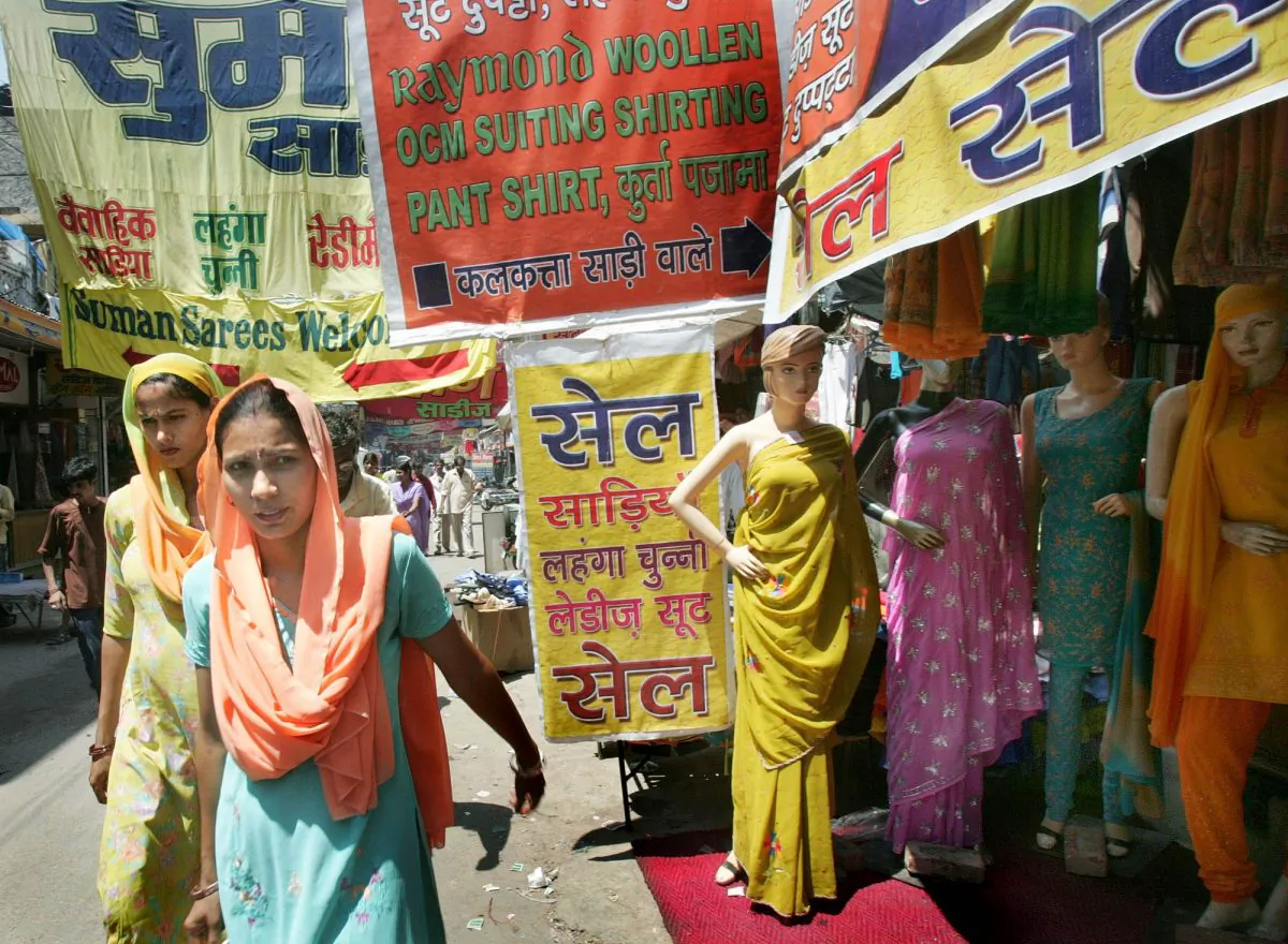 Women walk past a fabric shop at a market in Gurgaon, a suburb of New Delhi, India, Monday, Aug. 1, 2005.Youth in India are increasingly going under the knife to enhance their appearance and improve their self-confidence. (Gurinder Osan/AP Photo)