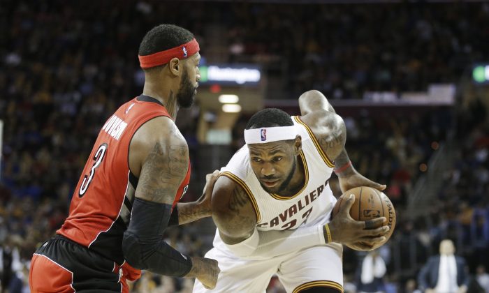 Cleveland Cavaliers' LeBron James, right, goes against Toronto Raptors' James Johnson (3) in the fourth quarter of an NBA basketball game Tuesday, Dec. 9, 2014, in Cleveland. (AP Photo/Mark Duncan)