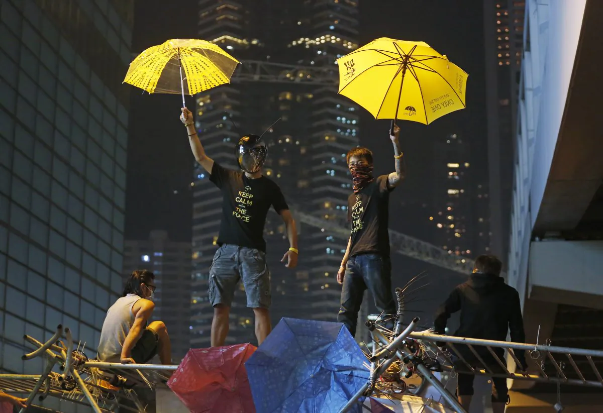 Protesters pose for photographs on a barricade at the occupied area outside government headquarters in Hong Kong Wednesday, Dec. 10, 2014. (AP Photo/Kin Cheung)