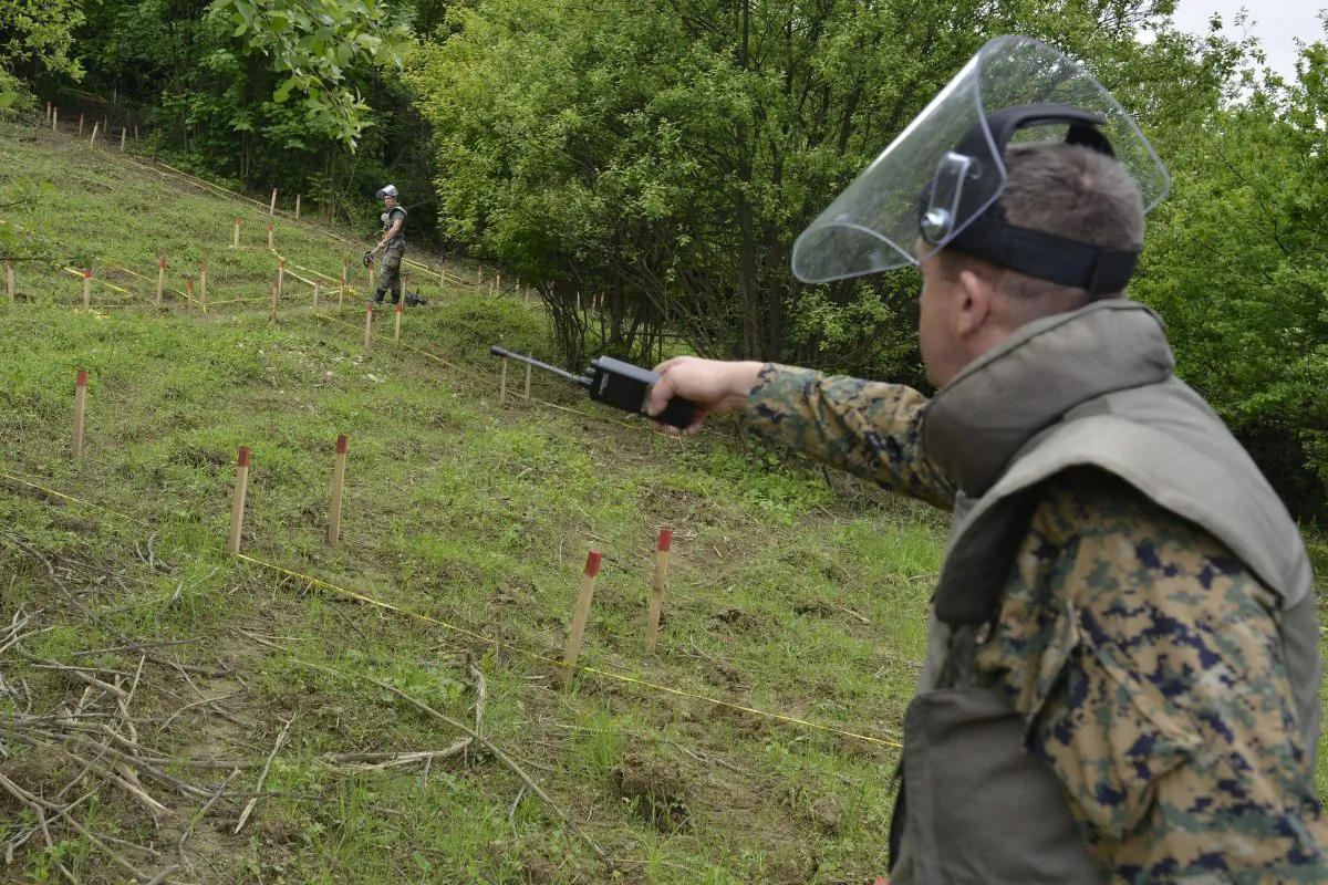 Bosnian soldiers repair warning signs and search for landmines in fields near the banks of the river Bosnia which flooded a town near Sarajevo, May 20. The flooding unearthed landmines left over from Bosnia’s 1992-95 war and washed away the signs that marked them. (AP Photo/Sulejman Omerbasic)