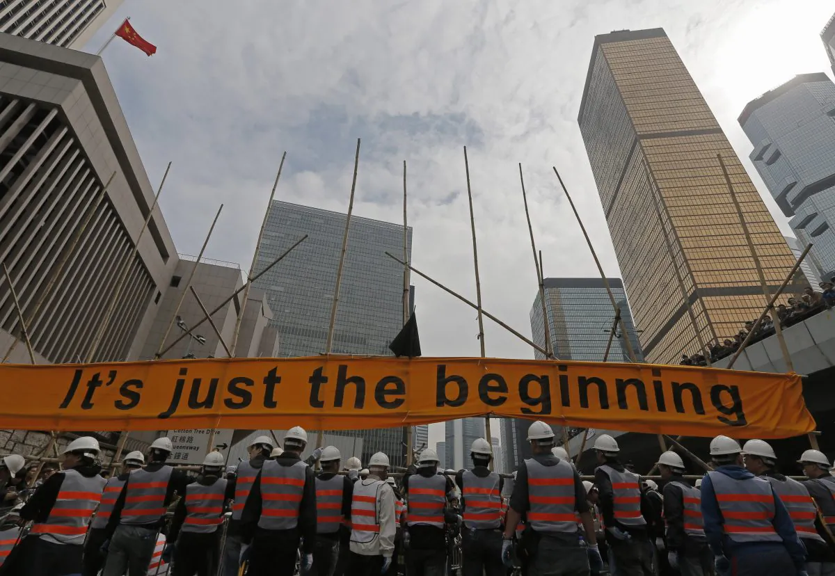 Workers clear barricades on a main road in an occupied area outside government headquarters in Hong Kong's Admiralty district Thursday, Dec. 11, 2014. (AP Photo/Vincent Yu)