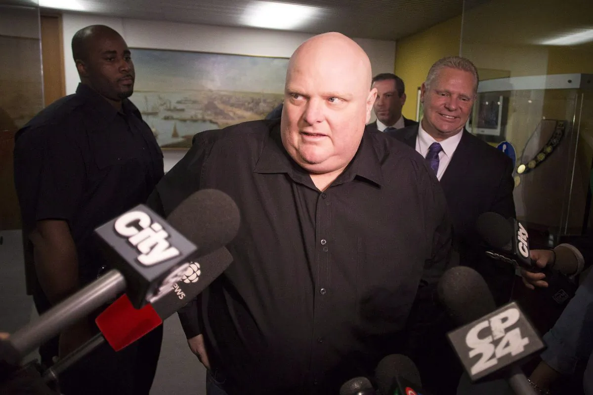 Toronto's outgoing Mayor Rob Ford (centre) stands next to his brother Doug Ford (right) outside his office as he scrums with the media before signing bobble heads in Toronto on Nov. 21, 2014. Rob Ford says he's due for a fifth round of chemotherapy next week but that if he beats cancer he'll take another run for mayor of Toronto. (The Canadian Press/Chris Young)