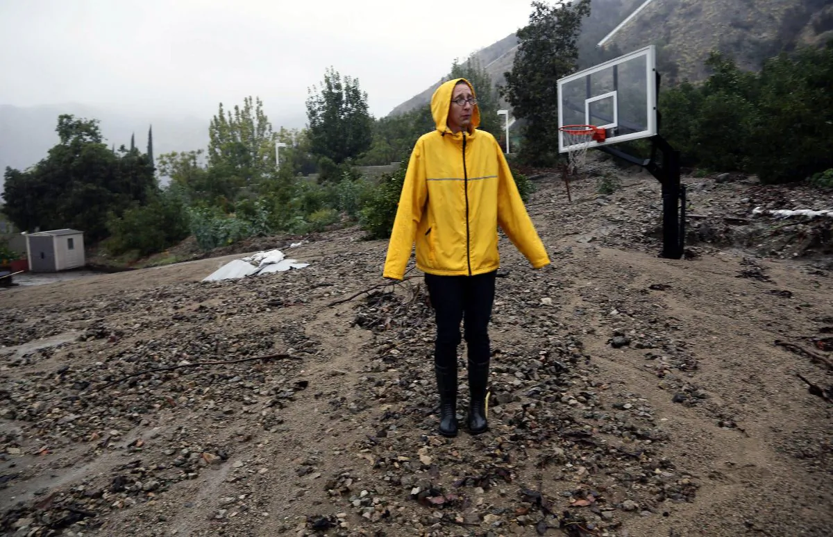 Homeowner Amanda Heinlein stands on a mud landslide covering a basketball court near her house in Azusa, Calif., Friday, Dec. 12, 2014. A soaking storm swept into California, causing several mudslides, flooding streets and cutting power to tens of thousands Friday after lashing the rest of the state with much-needed rain. (AP Photo/Nick Ut)