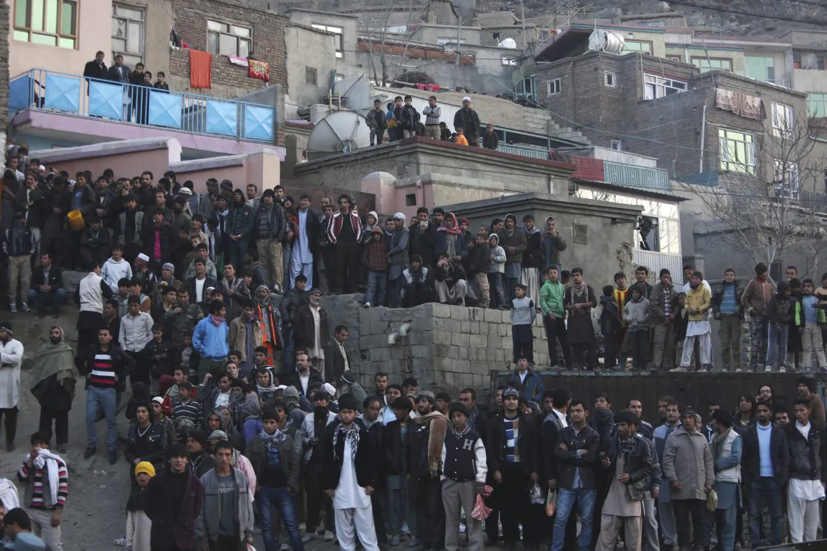 Bystanders look at the site of a suicide attack by the Taliban in Kabul, Afghanistan, Saturday, Dec. 13, 2014. A senior Afghan defense official said that the suicide bomber struck the Defense Ministry bus carrying Afghan Army personnel, killing several as violence in the country spikes just weeks before most international combat forces withdraw. (AP Photo/Rahmat Gul)