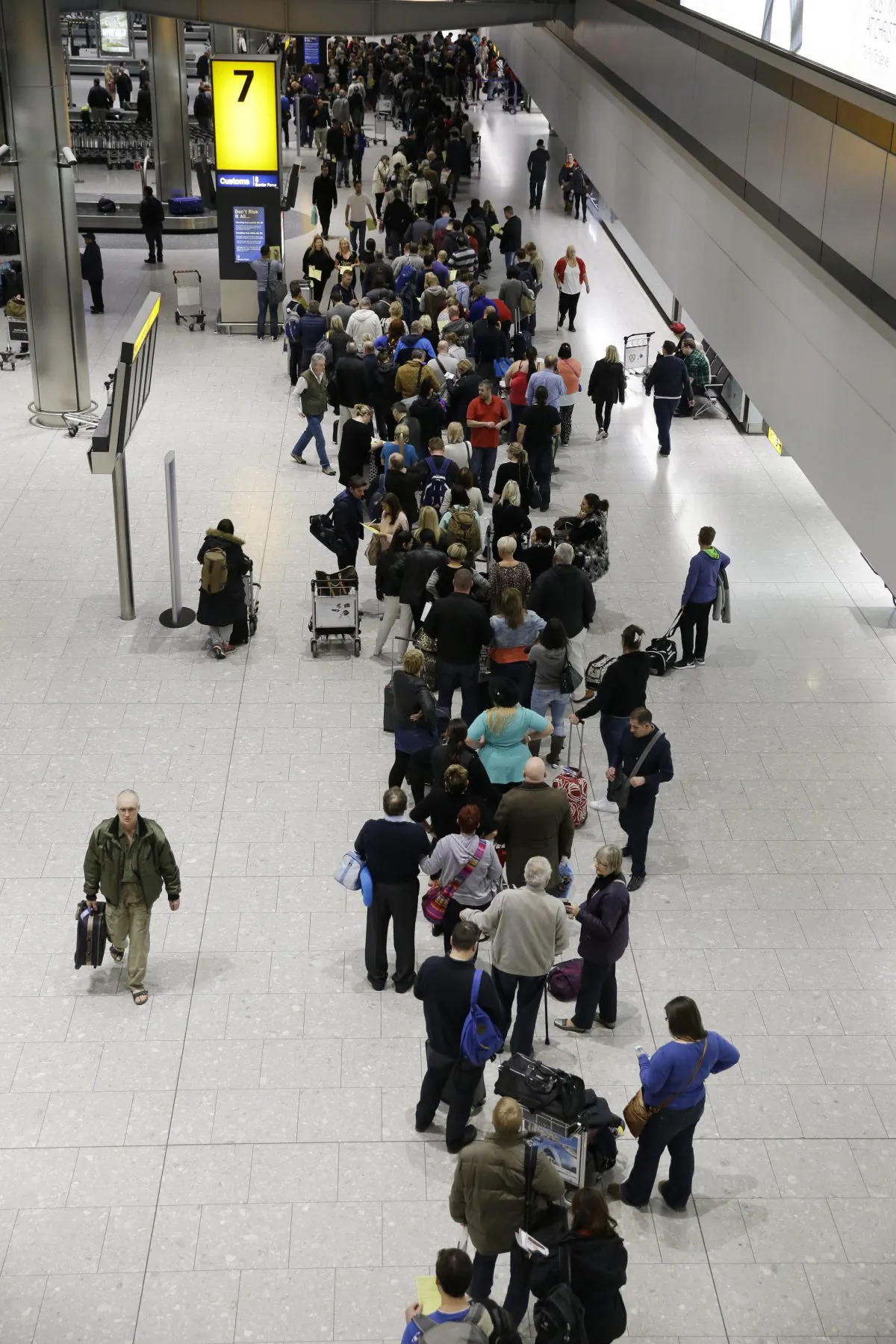 People queue in the luggage hall of Terminal 5 at Heathrow Airport in London, Friday, Dec. 12, 2014. London's airspace was closed today due to what authorities say was a computer failure at one of Britain's two air traffic control centres. Britain's national air traffic body says the computer problem that touched off troubles in the system has been fixed and it is in the process of returning to normal operations. (AP Photo/Matt Dunham)