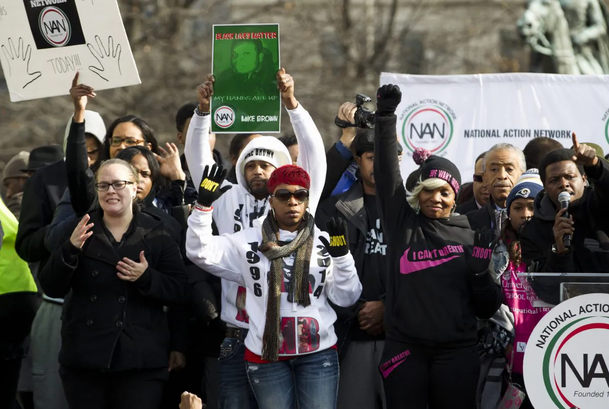 Lesley McSpadden (C), the mother of slain Ferguson teen Michael Brown, raises her hands at Freedom Plaza in Washington, Saturday, Dec. 13, 2014, during the Justice for All march and rally. More than 10,000 protesters are converging on Washington in an effort to bring attention to the deaths of unarmed black men at the hands of police. Civil rights organizations are holding a march to the Capitol on Saturday with the families of Michael Brown and Eric Garner, two unarmed black men who died in incidents with white police officers. (AP Photo/Jose Luis Magana)
