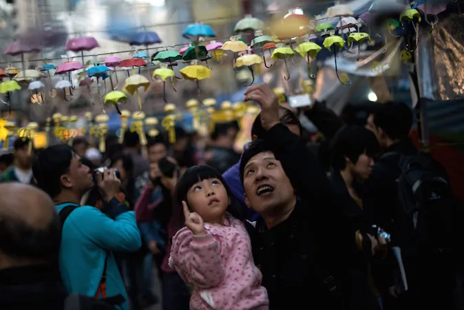 A man and his daughter pose for photos next to an installation of paper umbrellas -- symbols of the pro-democracy protests in Hong Kong -- in the Causeway Bay district of Hong Kong on December 14, 2014. (Alex Ogle/AFP/Getty Images)