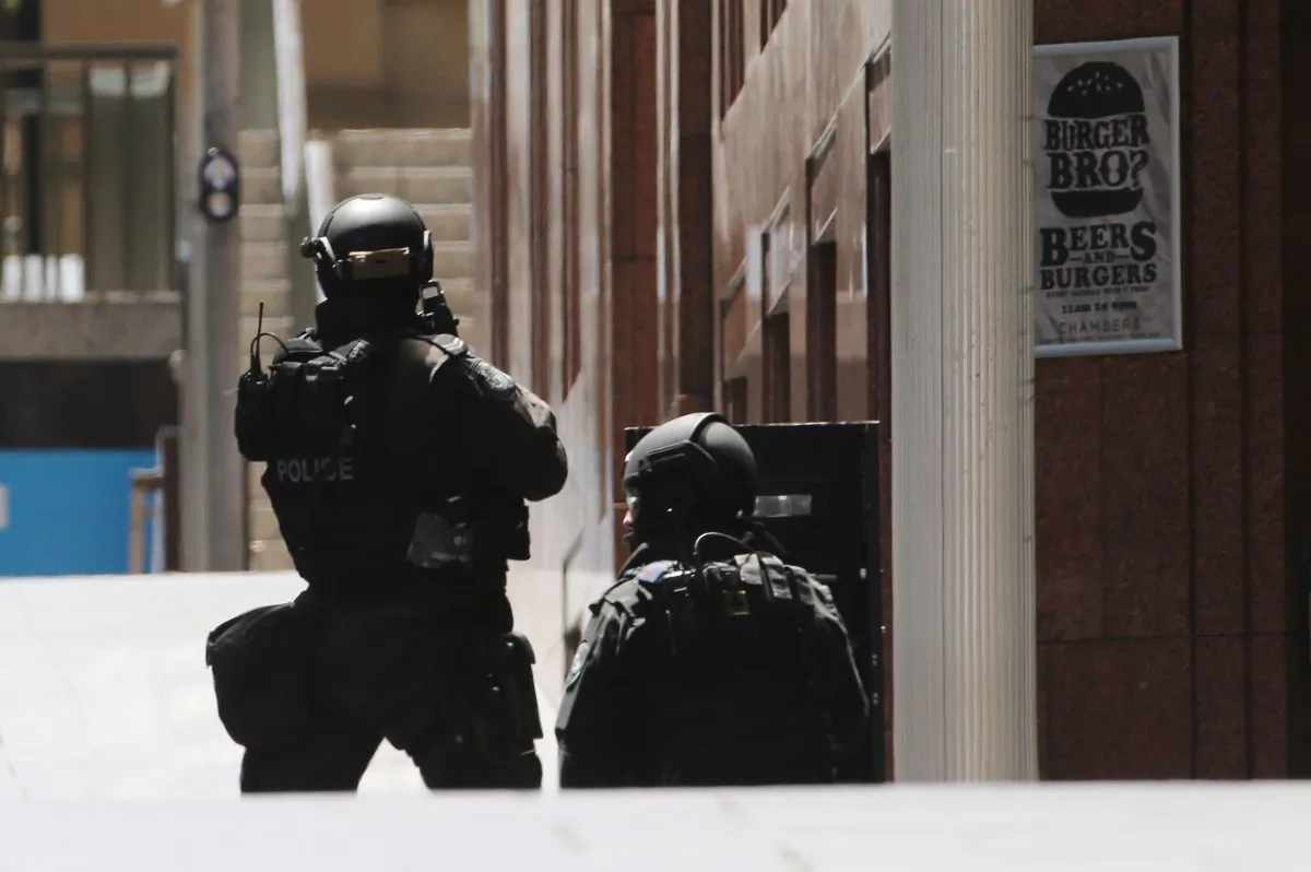 Police stand at the ready close to a cafe under siege in Martin Place in the central business district of Sydney, Australia, Monday, Dec. 15, 2014. (AP Photo/Rob Griffith)
