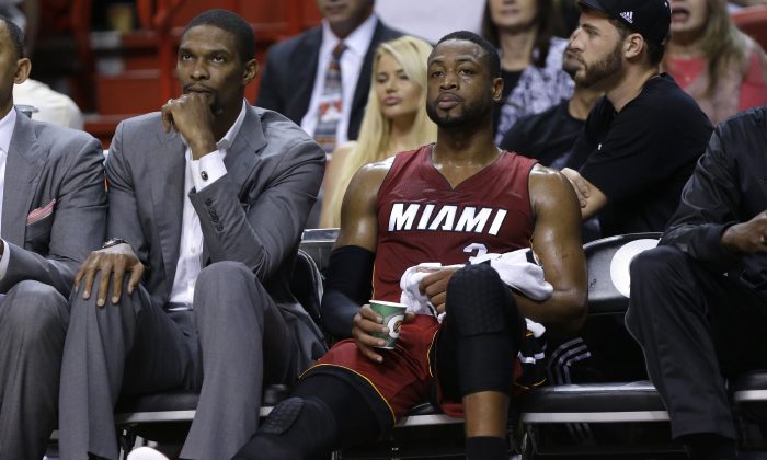 Miami Heat center Chris Bosh, left, watches from the bench with guard Dwyane Wade, right, in the first half of an NBA basketball game against the Chicago Bulls, Sunday, Dec. 14, 2014, in Miami. Bosh did not play due to a calf strain. (AP Photo/Lynne Sladky)