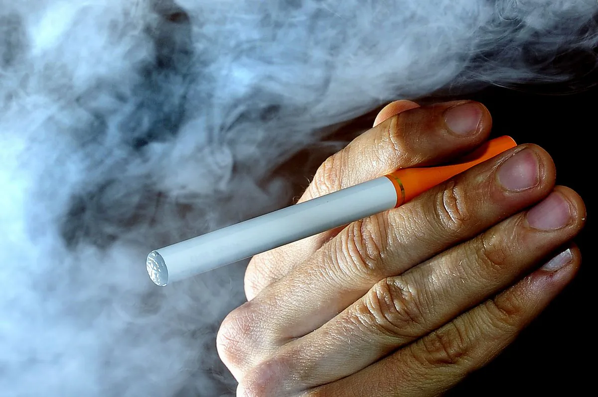 A person posing with an electronic cigarette, or e-cigarette. (AP Photo / Tim Ireland, PA)