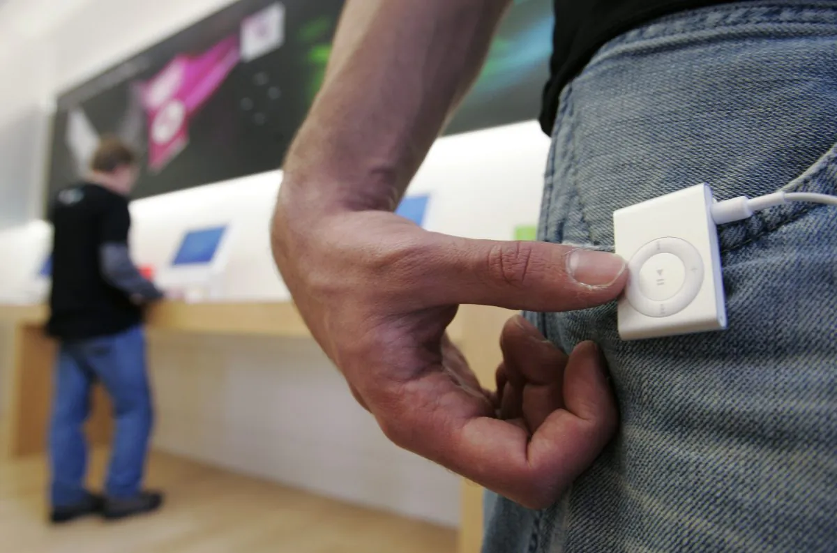 A man wears an Apple iPod Shuffle at an Apple store in Palo Alto, Calif., on Nov. 3, 2006. After just a few hours of deliberation, a jury in California on Tuesday, Dec. 16, 2014, found in favor of Apple in a billion-dollar class-action lawsuit over the price of its iPod music players. (AP Photo/Paul Sakuma)