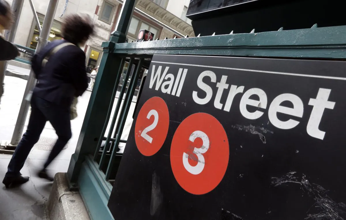 People pass a Wall Street subway stop, in New York's Financial District on Oct. 2, 2014. U.S. stocks are opening moderately lower Tuesday, Dec. 16, 2014, as the price of oil continues to drop. (AP Photo/Richard Drew)