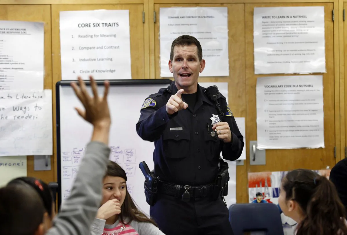 In this Tuesday, Oct. 28, 2014 file photo, Officer Phil White of the San Jose Police Department teaches a "Choices and Consequences" class for 5th grade students at Christopher Elementary School in San Jose, Calif. White is on leave as his department investigates comments posted online that threaten those protesting the recent deaths of unarmed black men in Ferguson, Missouri, and New York. In the tweets, White said he would kill anyone who threatens him or his family. He also said he would be off-duty at the movies with his gun if anyone "feels they can't breathe or their lives matter." (AP Photo/Bay Area News Group, Gary Reyes)