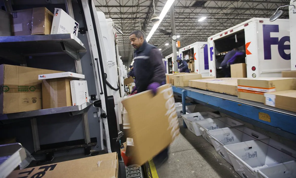 In this Dec. 15, 2014 photo, courier Stephen Werts loads packages onto a truck for delivery at a FedEx facility, in Marietta, Ga. FedEx reports quarterly financial results on Wednesday, Dec. 17, 2014. (AP Photo/David Goldman)