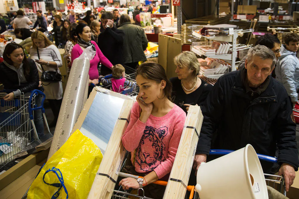 People wait in a line to pay for her purchases at the IKEA store on the outskirts of Moscow, Russia, Wednesday, Dec. 17, 2014. The collapse of the national currency triggered a spending spree by Russians desperate to buy cars and home appliances before prices shoot higher. Several car dealership were reported to have suspended sales, unsure how far down the ruble will go, while Apple halted all online sales in Russia. (AP Photo/Pavel Golovkin)