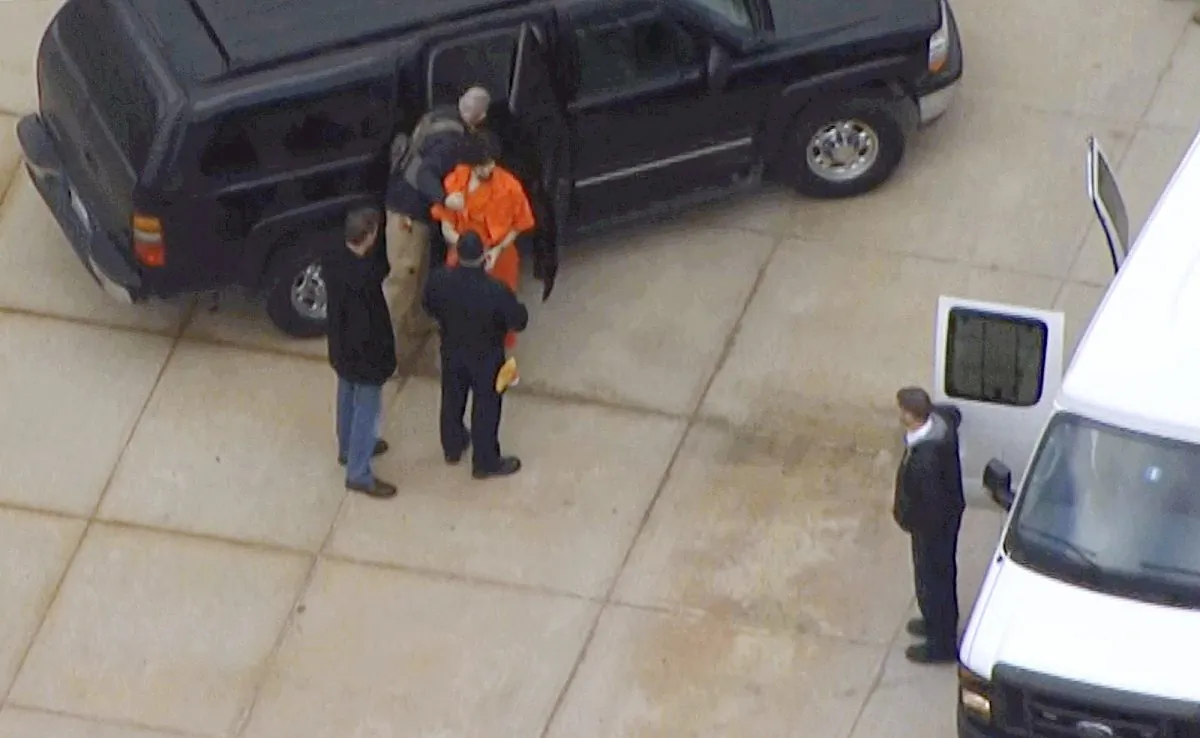 In this still images from aerial video provided by WHDH-TV in Boston, Boston Marathon bombing suspect Dzhokhar Tsarnaev, center wearing an orange jumpsuit, is transferred between vehicles in Devins, Mass., following his hearing in federal court Thursday, Dec. 18, 2014, in Boston. Tsarnaev is charged with carrying out the April 2013 attack that killed three people and injured more than 260. He could face the death penalty if convicted. (AP Photo/WHDH-TV Boston)